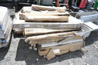 Cardboard boxes containing scratch and dent items including a Steelton Utility Wire Shelf Kit and various components.
