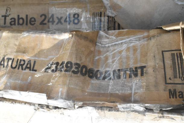 Cardboard box with visible labels reading "Table 24x48" and "NATURAL #3493060ANTNT," indicating contents.