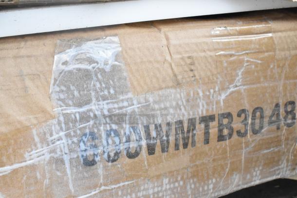 Cardboard packaging labeled "6COWMTB3048" containing scratch and dent items, includes pan racks and stainless table.