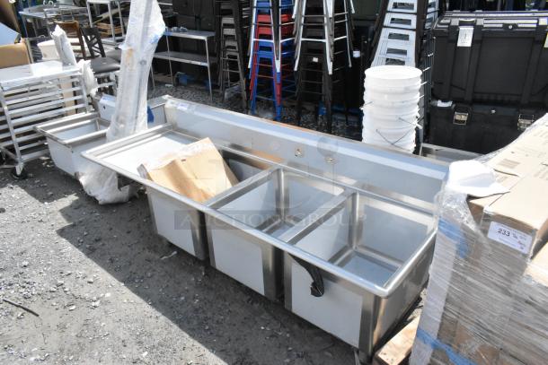 BRAND NEW Regency 600S3182424L stainless steel 3 bay sink with left side drain board, minor scratches and dents visible.