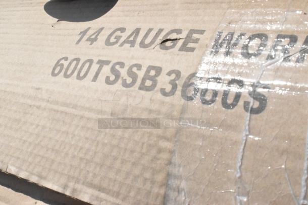 Cardboard box marked "14 Gauge Work" and "600TSSB3660S," indicating contents like a stainless steel table.