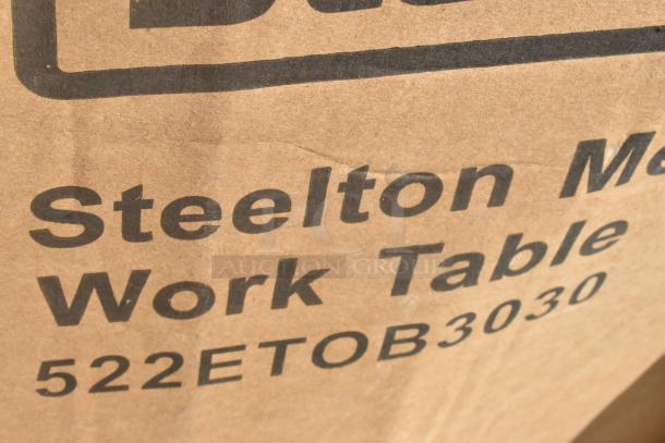 Cardboard box with "Steelton Metal Work Table 522ETOB3030" printed on it, indicating a new work table.