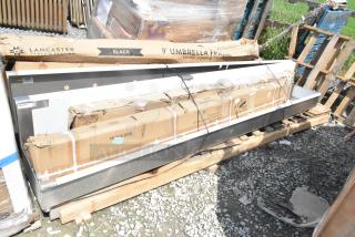 6 brand new scratch and dent items on pallets, including a wall mount sink, shelf, and umbrella frame. Lancaster Table & Seating box visible.