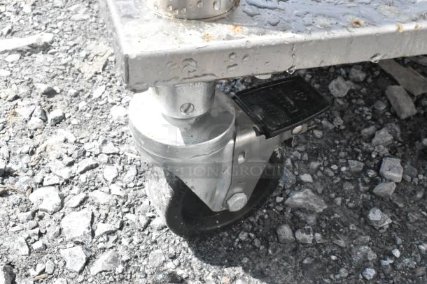 Stainless steel equipment stand with under shelf and commercial casters, featuring a sturdy metal design and locking wheel.