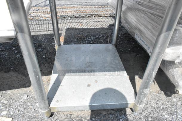 Stainless steel equipment stand with metal under shelf; used condition, sturdy construction, visible marks.
