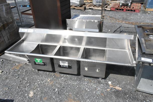Regency 600S31515215 stainless steel 3-bay sink with dual drain boards, no legs, labeled "Wash" and "Rinse."
