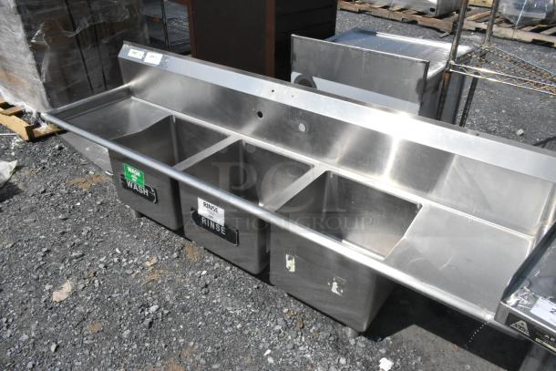 Regency 600S31515215 stainless steel 3 bay sink with dual drain boards, missing legs, visible wash and rinse labels.