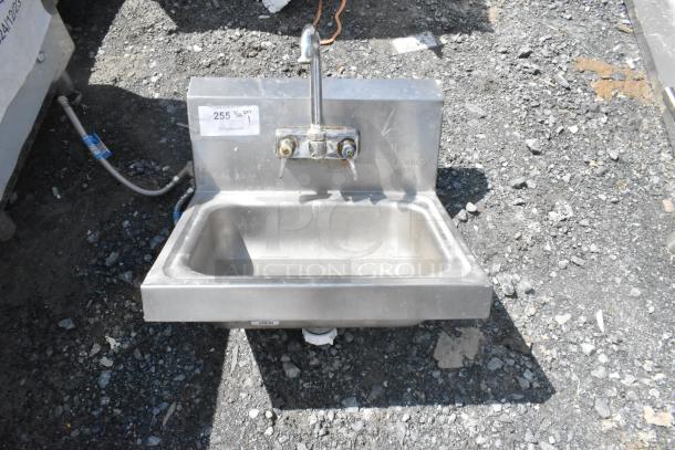 Stainless steel single bay wall mount sink with faucet and handles, lightly used, includes visible connection pipes.