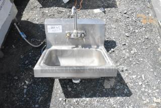 Stainless steel single bay wall mount sink with faucet and handles, lightly used, includes visible connection pipes.