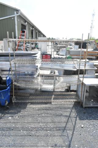Chrome finish 4-tier wire shelving unit in outdoor setting. Buyer must dismantle. For freight consideration only.