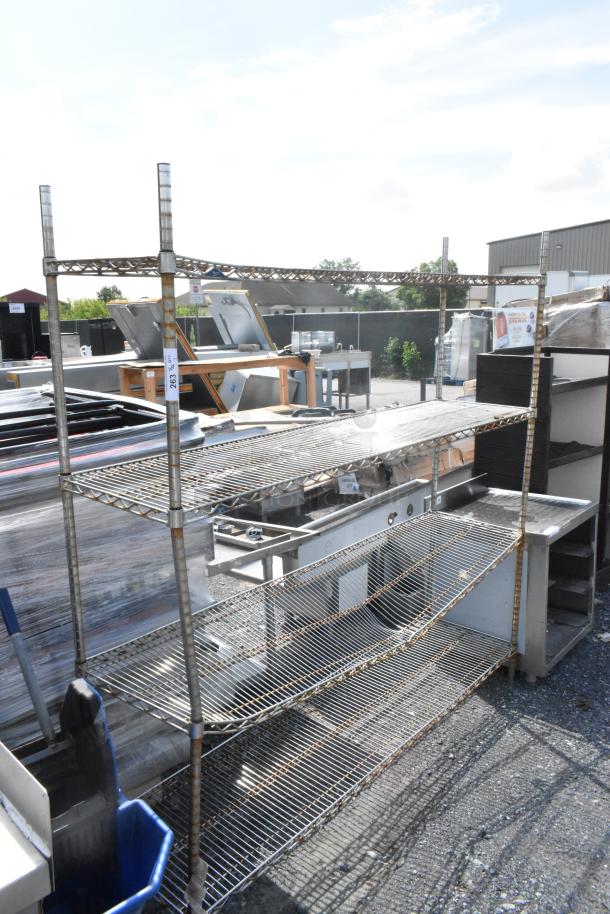 Chrome finish 4-tier wire shelving unit, outdoor setting. Buyer must dismantle; freight charges apply. Signs of wear.