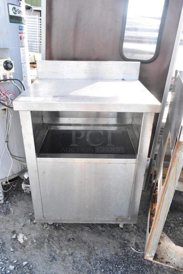 Stainless steel table with open storage compartment, industrial design, used condition, minor surface wear visible.