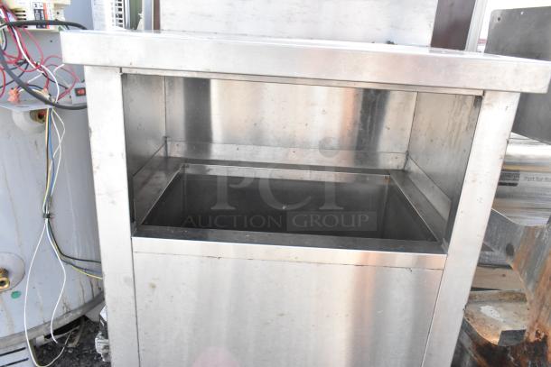 Stainless steel table with open top and lower storage space, in used condition. Minor surface marks visible.