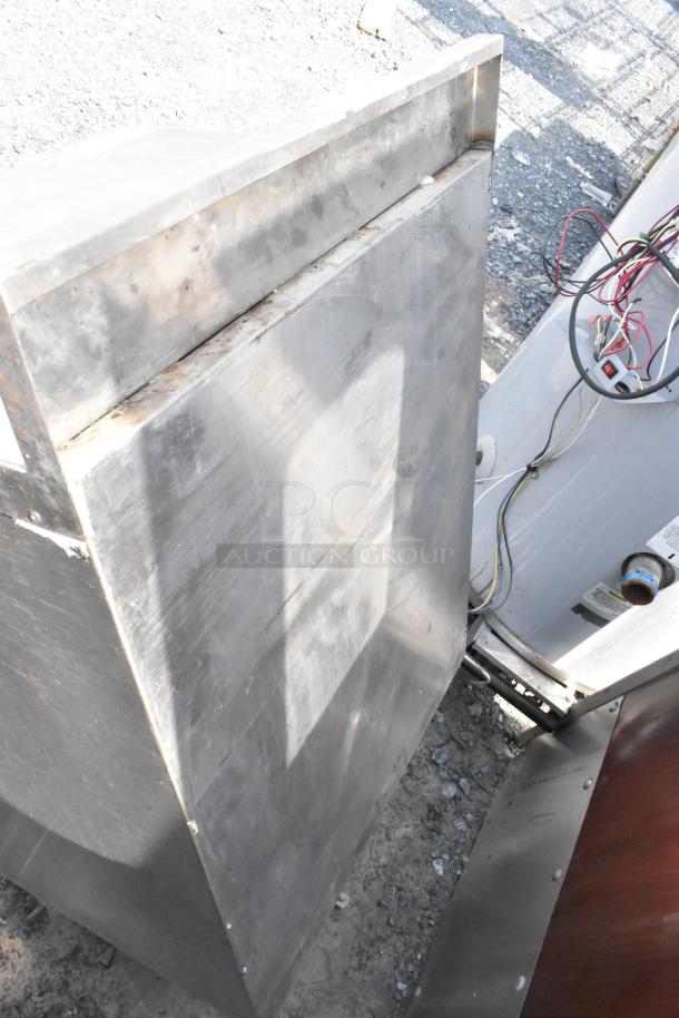 Stainless steel table with a robust build, visible wear and rust marks, suggesting outdoor use, no visible labels.