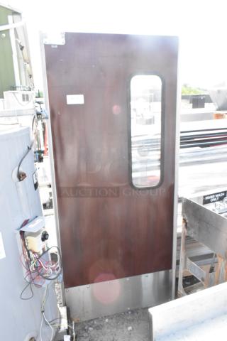 Dark wood swinging kitchen door with window, stainless steel kick plate, and visible label "267." Used, good condition.