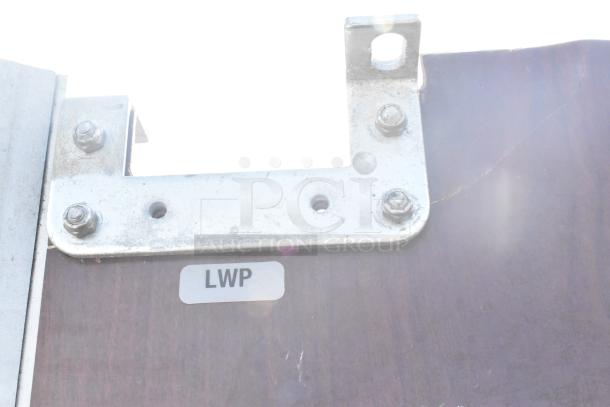 Metal hinge and mounting hardware of a swinging kitchen door, labeled "LWP," attached to a wooden panel.