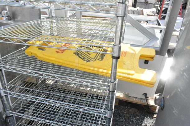 Chrome finish 8-tier wire shelving unit with wet floor signs. Buyer must dismantle. Consider freight charges.