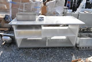 Stainless steel table with under shelves and contents, features metal bins on top, sturdy construction, in used condition.