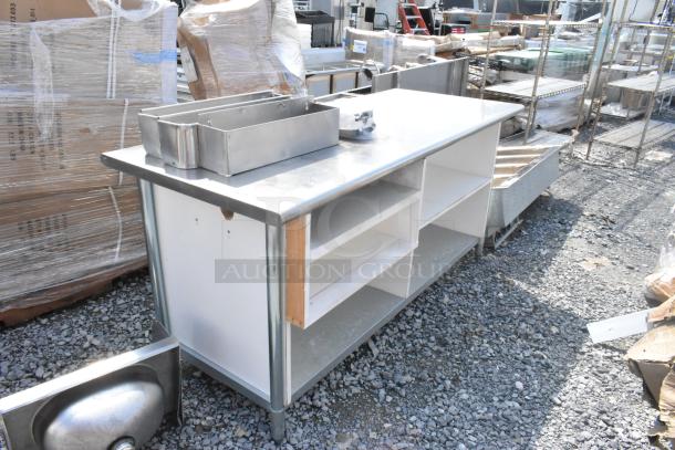 Stainless steel table with under shelves and contents, includes storage bins. Used condition, outdoor auction setting.