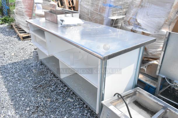 Stainless steel table with under shelves, minor wear, includes metal containers and packed contents on top.