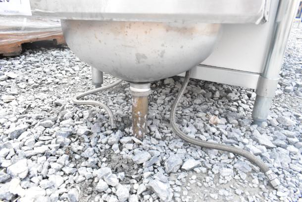 Stainless steel single bay wall mount sink with side splash guards, faucet, and handles. Used condition, visible plumbing connections.