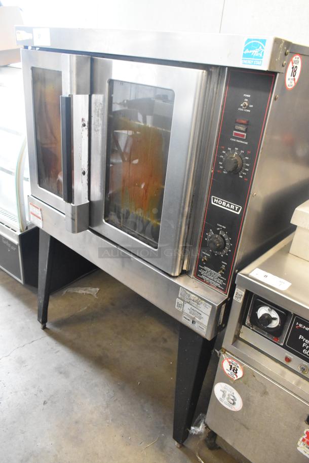 Hobart stainless steel commercial convection oven with view-through doors, metal racks, thermostatic controls, on metal legs.