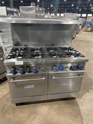 Standard Range stainless steel 8-burner gas range with double oven, backsplash, overhead salamander shelf, and wire rack on casters.