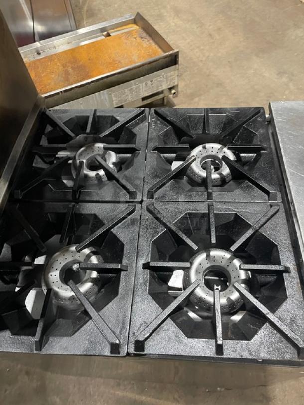 American Range stainless steel 4-burner gas range/oven combo with backsplash, salamander shelf, and wired oven rack on casters.