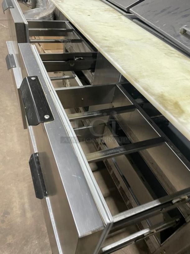 Beverage-Air SPED6024M4 stainless steel prep table with 4 refrigerated drawers, cutting board, and casters. Visible open drawers.
