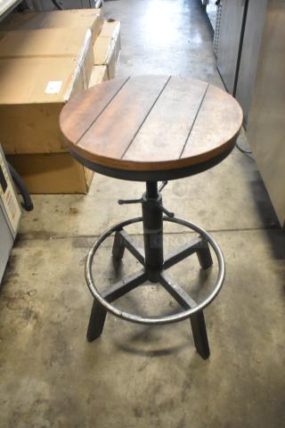 Wooden and metal stool with round wooden seat, adjustable black metal base, and footrest. Industrial style, good condition.