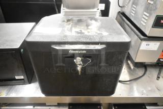 SentrySafe black single compartment safe in worn condition, includes a key; logo visible on front.