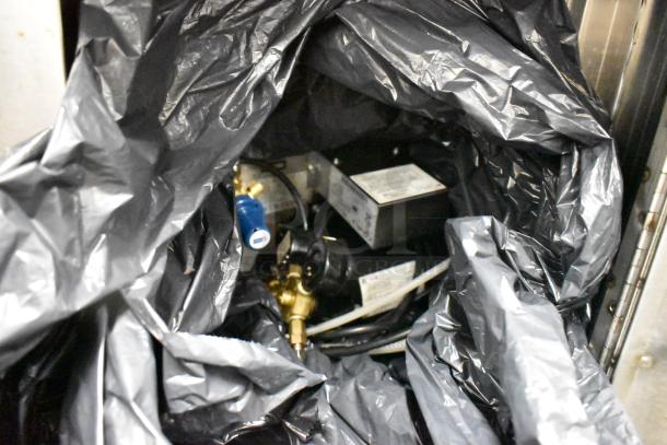 Close-up of interior mechanics under plastic in stainless steel counter, showing hoses and wiring.