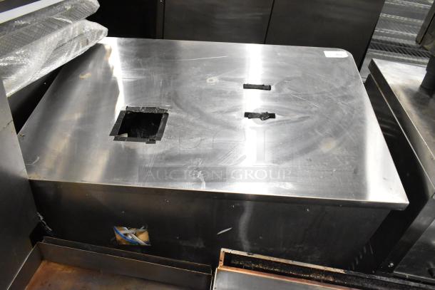 Stainless steel counter with three doors, under shelf, visible surface wear, and cutouts, ideal for commercial use.