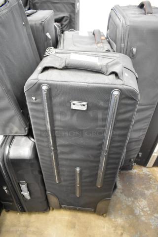 Black soft case on casters, zippered top, metal accents, used condition. No visible brand name or markings.