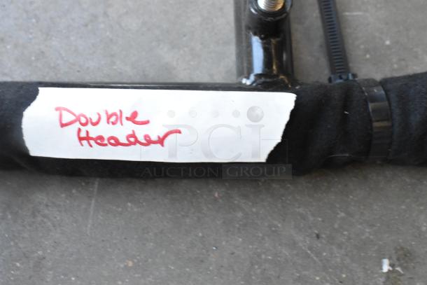 Lot of metal pieces labeled "Double Header," featuring a black pipe with a visible label. Ideal for collectors or metalwork.