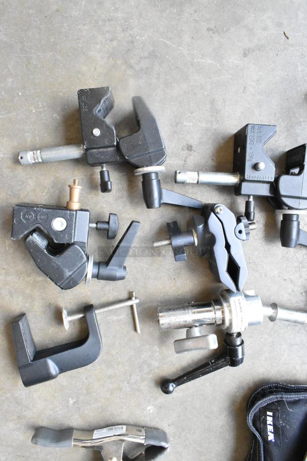 Lot of various clamps in a hard bin. Includes brands like Manfrotto. Good condition with visible model markings.