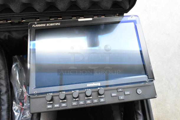 Flanders Scientific Zunzheng BM090 broadcast monitor in a hard case, includes wires. Features control buttons and clear display.