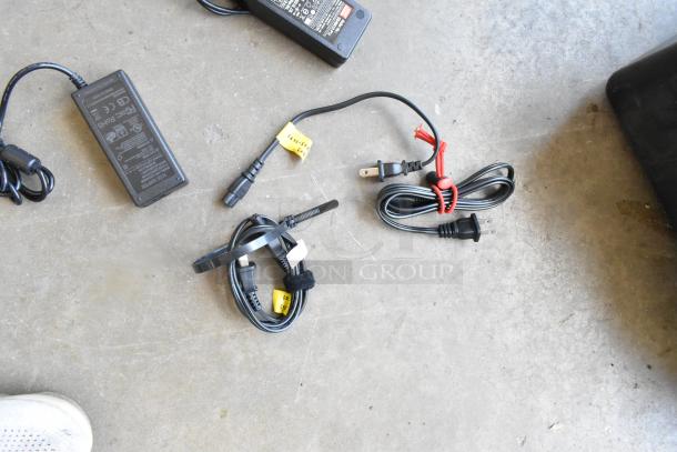 Cables for Flanders Scientific Zunzheng BM090 monitor, includes power adapter, in used condition on concrete surface.