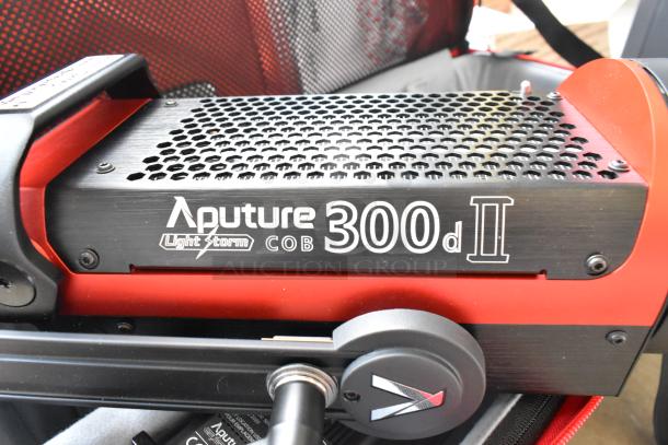Aputure Light Storm COB 300d II monolight in excellent condition, with red accents, shown in its protective carrying case.