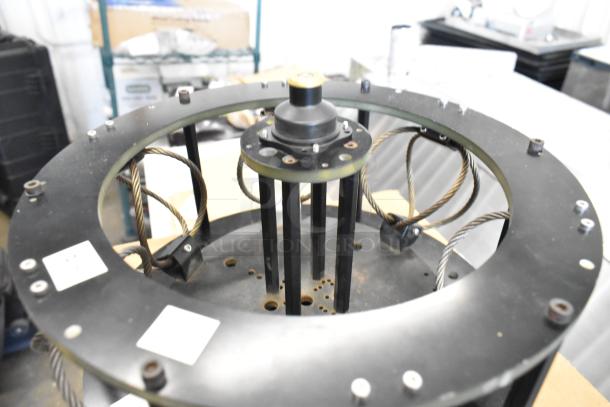 Industrial vibration isolator, circular metal frame, coiled cables, fair condition, technical markings visible.