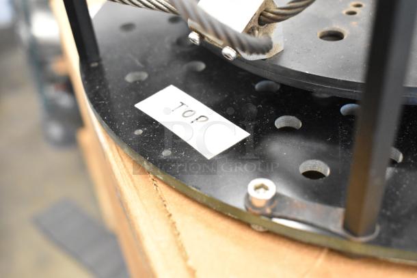 Black metal vibration isolator with a "TOP" label, featuring perforated design and secured cable. Appears in good condition.