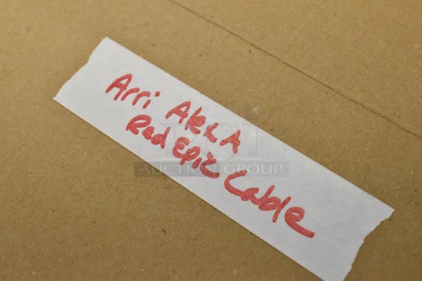 Handwritten label on cardboard reads "Arri Alexa Red Epic Cable," indicating included cable for auction.