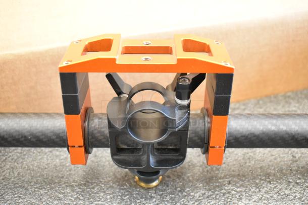 Freefly Movi Pro gimbal part, featuring an orange metal frame and black carbon fiber rod, used for stabilizing cameras.