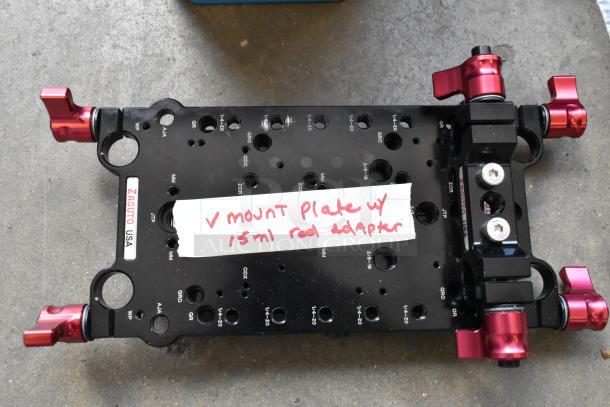Zacuto USA V Mount Plate with 15mm rod adaptor, metal construction, red knobs, multiple threaded holes, handwritten label.