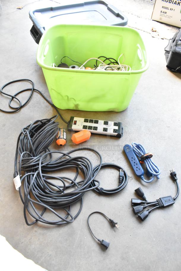 Lot of various wiring and power strips in a green poly bin, includes cords and power strips in used condition.