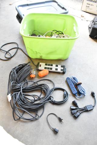 Lot of various wiring and power strips in a green poly bin, includes cords and power strips in used condition.