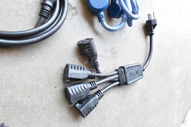 Lot of wiring and power strips in poly bin, featuring black cables with multiple plug connectors; includes a blue fabric-covered cord.