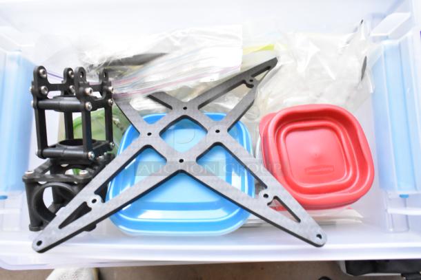 Assorted items in a poly bin, including a Movi Pro Pop-n-Lock bracket, colorful storage containers, and plastic bags.