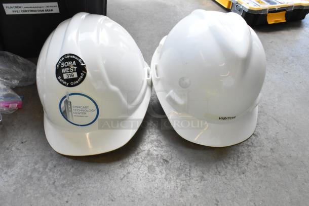 Lot of high visibility vests, safety glasses, and hard hats in poly bin. Hard hats with safety-oriented labels.