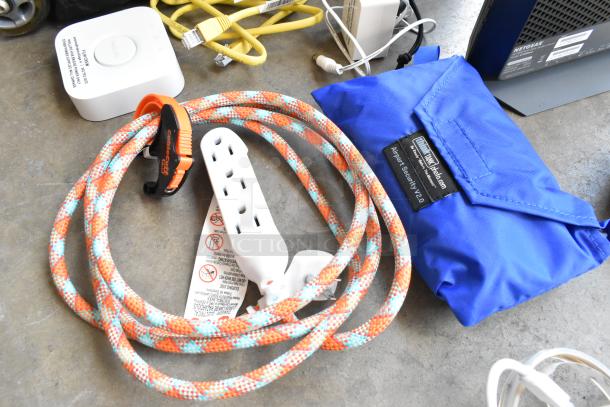 Think Tank soft bag with label "Airport Security V2.0," colorful power cord, and electronic accessories on concrete surface.